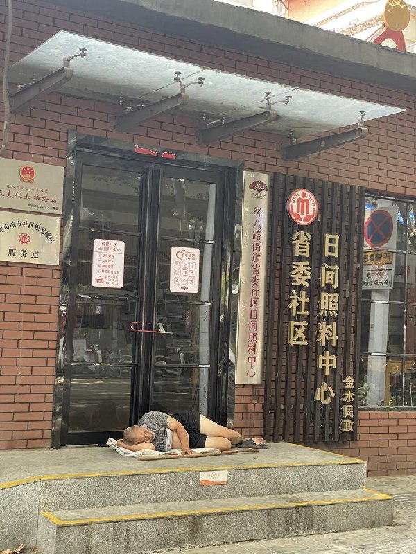 网友投稿：郑州金水，日间照料中心省委社区门口，一位老人席地而睡