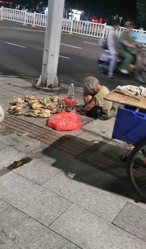 “人间就是地狱”近日，一网友发帖，一位白发苍苍的老人疲惫地蜷缩坐在城市夜晚的地上，叫卖的香蕉已经开始发黑