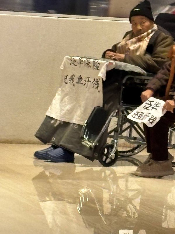 网友投稿：近日，西安市雁塔区禾盛京广中心A座大厅内，一名老人推着另一名坐轮椅的老人举标语维权，标语内容为“泛华保险还我血汗钱”
