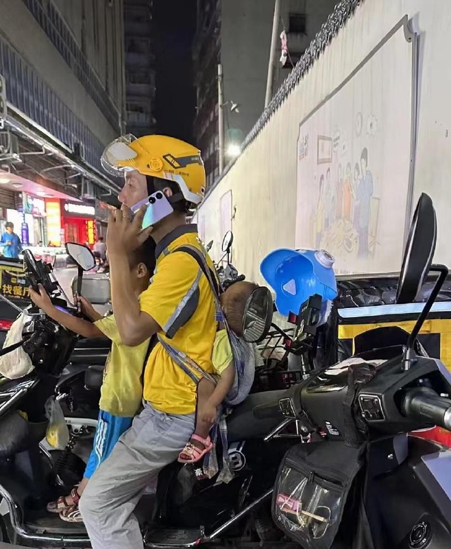 4月3日，广西，一名网友拍下这样一幕：一位外卖员带着两个孩子送外卖，车前坐着一个孩子，背上还背着一个孩子