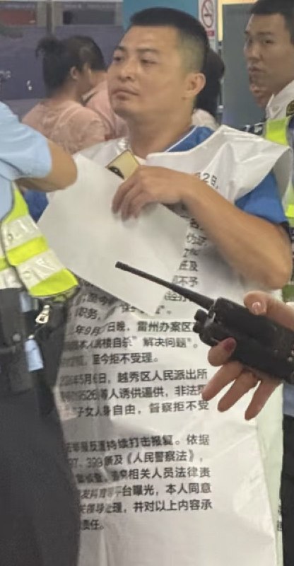 7月27日，广州体育西路，一名身穿印有申诉内容背心的男子被多名制服人员围住并带离现场
